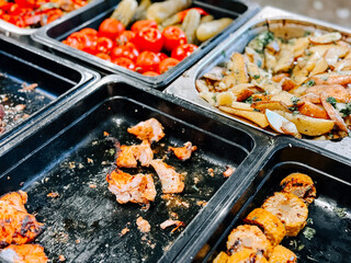 Grilled vegetables and meats laid out in mixed trays at an outdoor gathering