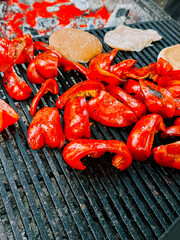 Grilling red peppers and patties on an outdoor barbecue at a sunny gathering