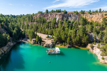 Turquoise water in a former quarry surrounded by forested cliffs.