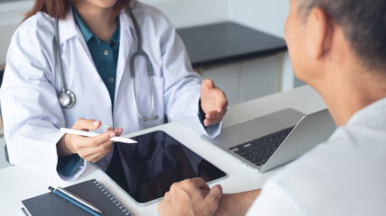 Doctor and patient in appointment at doctor office with advice. Doctor talking to patient and using...