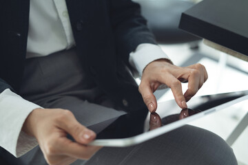 Closeup, business woman using digital tablet, finger touching on screen, reading e-document at office. Woman using tablet computer, surfing the internet, searching the information, internet networking