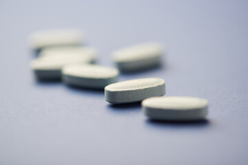 Multivitamin tablets on bright paper background. Close up. Copy space	