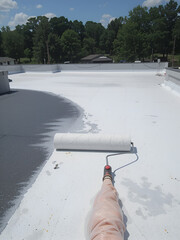 Using a roller brush to apply a waterproof coating to a rooftop. Generated image