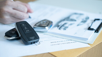 Pen and car keys placed on documents showing the process of signing an automobile sales contract and official ownership transfer