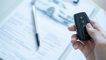 Vehicle remote keys with documents on the desk representing contract signing automobile sales deal and professional business process