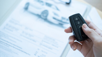 Closeup of car keys and pen on contract papers showing vehicle purchase agreement transaction and transfer of ownership