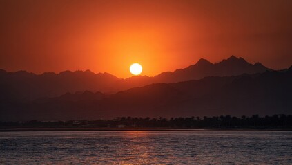 Sunset over mountains by a calm sea