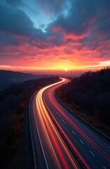 Highway leading towards a city at sunset. Dramatic sky with vibrant red and orange clouds, sun setting on horizon. Light trails from cars indicate fast motion on asphalt road.