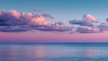 Obraz premium Calm seascape at sunset with soft clouds. Pastel pink and purple hues paint the sky and water. A tranquil horizon