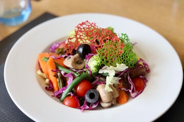 A bowl of fancy salad served on a white plate