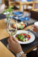 Wine or champagne in a glass with bright restaurant background with food on the side