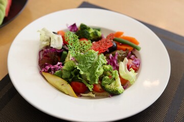 A bowl of fancy salad served on a white plate