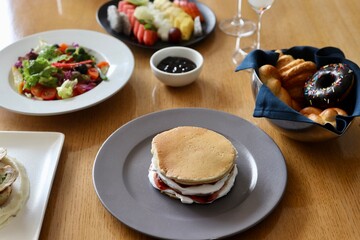 Pancake with maple syrup & honey with cream and other toppings on a table 
