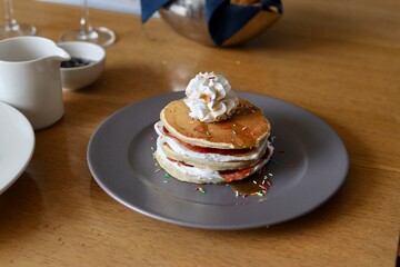 Pancake with maple syrup & honey with cream and other toppings on a table 