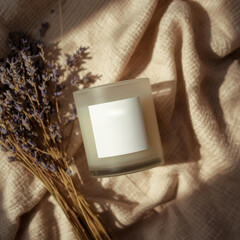 Scented candle in frosted glass jar sits on textured fabric beside dried lavender, creating cozy atmosphere