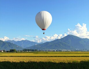 Fototapeta premium White hot air balloon floats above golden rice paddies, mountain backdrop