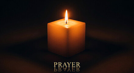 A single lit candle glows in the darkness casting a warm light and a reflection on a dark surface symbolizing prayer and hope