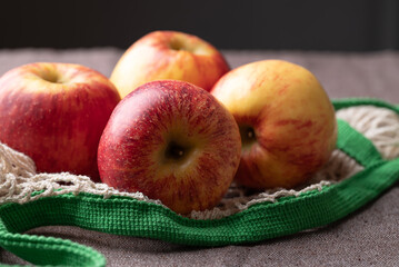 Red apple fruit (Envy apple) in mesh bag on brown fabric background