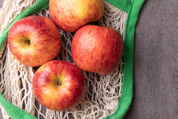 Top view of red apple fruit (Envy apple) in mesh bag on brown fabric background