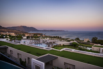 Seaside resort at sunset, view of coastline with swimming pools and buildings