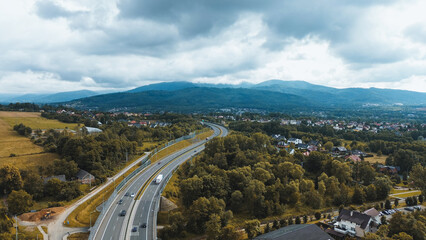 Aerial view of winding road through lush green landscape with houses