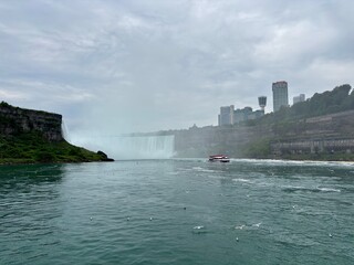 Boat navigates the churning waters below Niagara Falls on overcast day