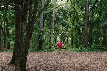 Girl in big forest playing disc gold and being active, having fun