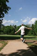Teenager throws disc golfing disc on summer day in green outdoors
