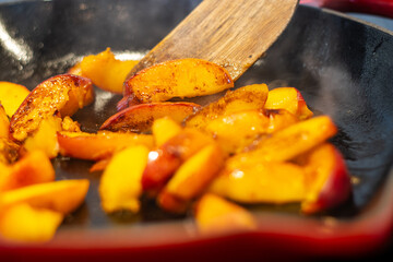 Caramelizing peach slices in a hot skillet with steam rising