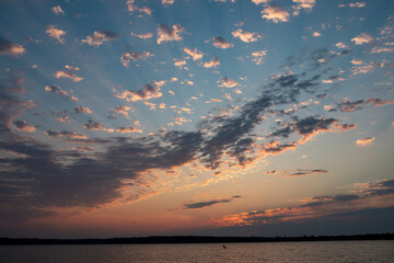 Colorful sunrise sky over calm lake with scattered clouds