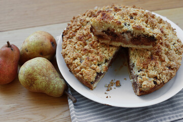 Traditional italian cake Sbrisolona cut in slices made with ricotta cheese, pear fruits and chocolate on a plate on wooden table