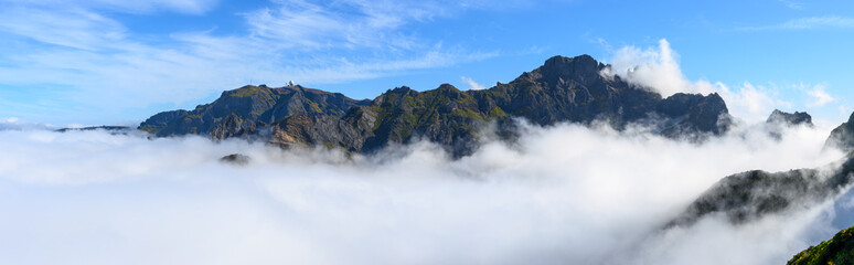 The clouds lie in the valley in front of Pico do Areeiro and Pico das Torres mountains on the PR1