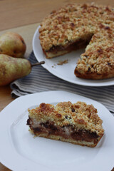 Traditional italian cake Sbrisolona cut in slices made with ricotta cheese, pear fruits and chocolate on a plate on wooden table