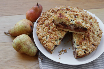 Traditional italian cake Sbrisolona cut in slices made with ricotta cheese, pear fruits and chocolate on a plate on wooden table