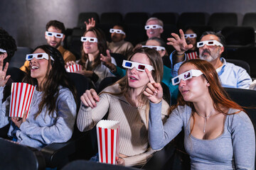 Multi ethnic group of friends enjoying a 3d movie at the cinema, reacting with enthusiasm and...