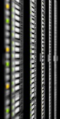 A blurred, high-angle view of server racks shows rows of gray panels with illuminated green and yellow lights against a dark background