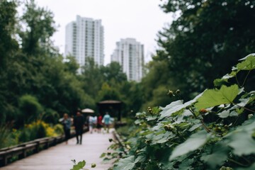 Obraz premium Blurred perspective of a pedestrian walkway through a lush park, with tall buildings visible in the distance on an overcast day