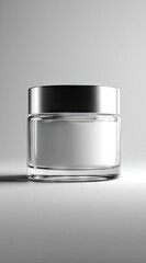 A cylindrical clear glass jar with a silver lid, sits on a white surface against a bright background, casting a subtle shadow