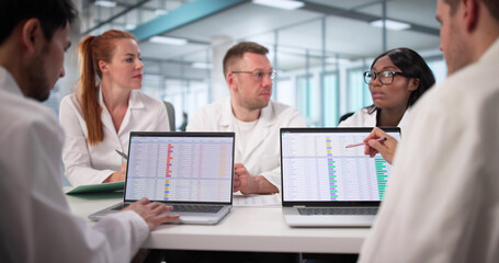 Busy Hospital Doctor Reviews Medical Billing Codes On Computer Spreadsheet