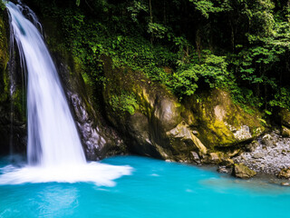 Fototapeta premium Scenic waterfall with turquoise water in lush forest, peaceful natural landscape, ideal for travel, adventure, and nature photography.