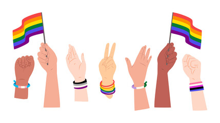 Diverse group of raised hands with different skin tones celebrating LGBTQIA+ pride with flags and identity bracelets