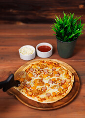 Tasty chicken and sausage crispy pizza on wooden plate using pizza cutter to slice delicious melting mozzarella cheese on board homemade cooking ingredient lying on dark background, food advertisement