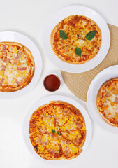 Top view of composition different delicious tasty crispy pizza, flatbread baked on white dish with decoration on table, homemade cooking ingredients lying on light background, food advertisement