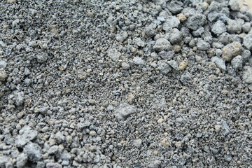 Pile of fine gray sand or aggregate used for construction, captured in natural light, showing granular texture and earthy tones, ideal for industrial or material background use.