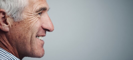 Fototapeta premium The Man in Profile Smiling Thoughtfully Against a Neutral Background with Warm Expression