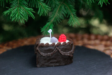 Handmade beeswax candle shaped like a chocolate cake slice with berries. Realistic dessert-style...