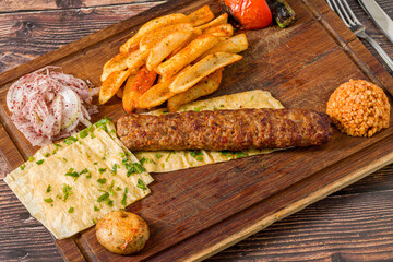 Traditional Adana kebab with fries, lavash, bulgur and onion salad