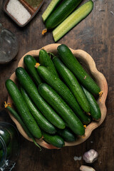 Fresh cucumbers with water droplets in rustic bowl on wooden table