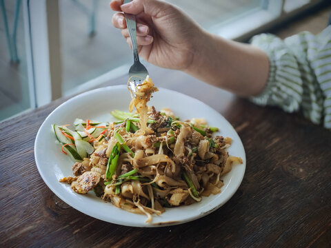 a plate of fried kwetiau noodles with vegetables
