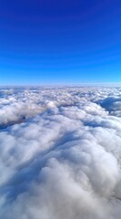 Naklejka premium A high-angle view presents a sea of fluffy white clouds under a clear, vibrant blue sky. Suggestive of flight or looking down from a great height